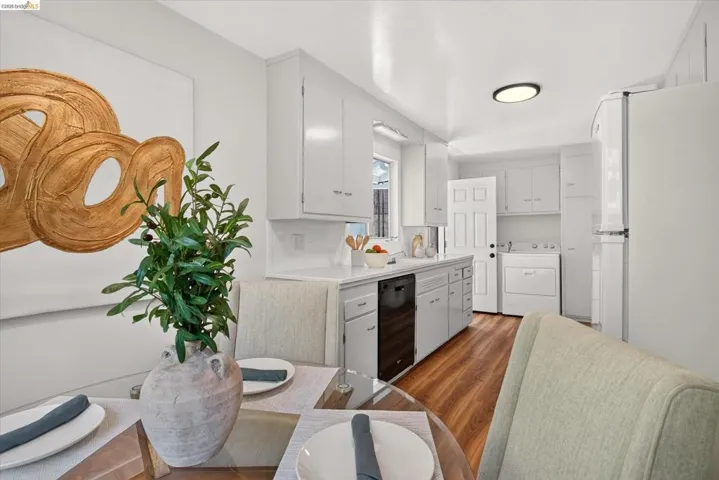 Galley kitchen featuring white cabinetry, a white tile backsplash, a black dishwasher, and wood-finish flooring