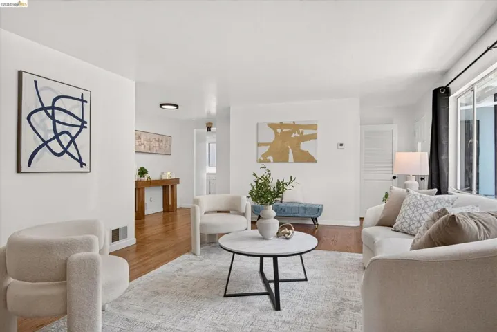 Bright living area featuring wood-finish flooring, white walls, and a large sliding glass door