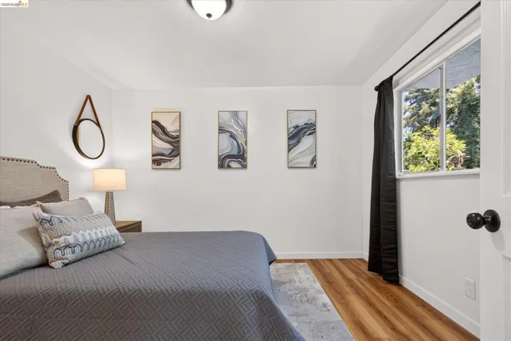 Bedroom featuring wood-finish flooring, a double-paned window, and a flush-mount ceiling light fixture