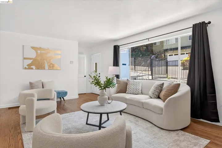 Bright living area featuring large sliding glass doors, rich wood-finish flooring, white walls, and a recessed ceiling