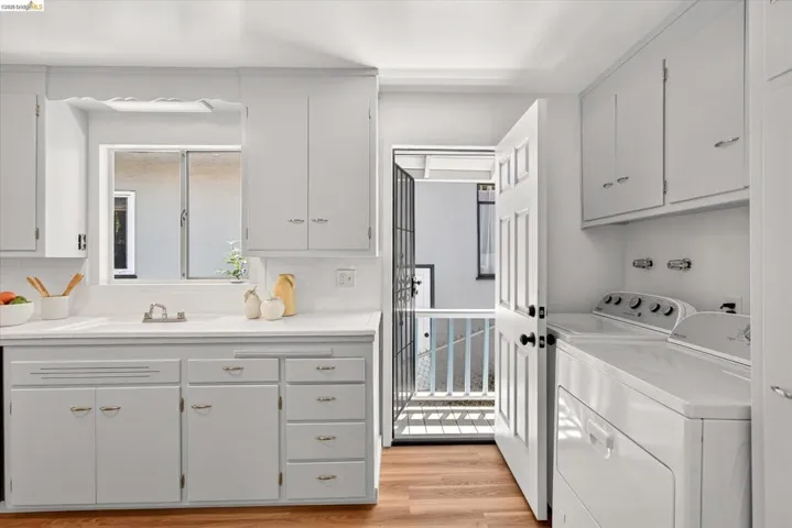 Bright kitchen with white cabinetry and wood-finish flooring