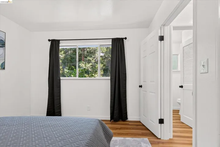 Bright room featuring wood-finish flooring and a white paneled door with matte black hardware