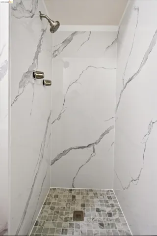 Walk-in shower with large-format wall tiles featuring a marble-inspired design