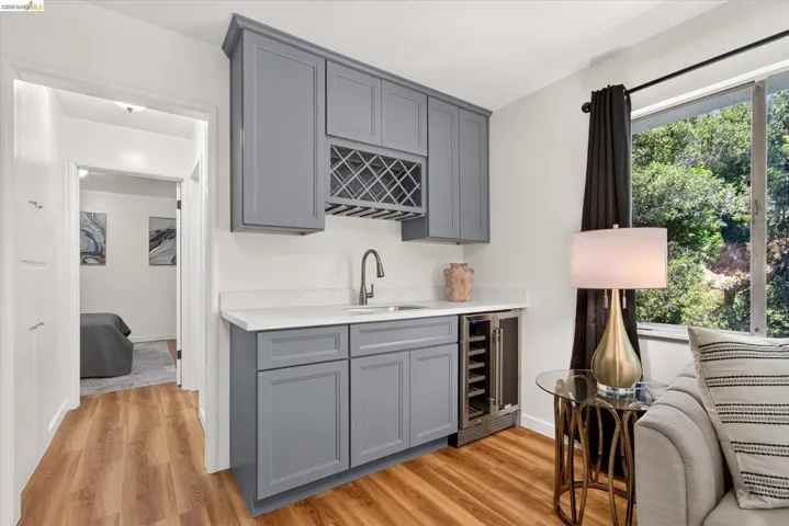 Dedicated wet bar featuring gray shaker-style cabinetry, a built-in wine rack, light-toned countertop, and undermount sink