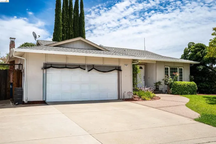 Single-story residence featuring an attached two-car garage, concrete driveway, and a decorative walkway leading to the front entry