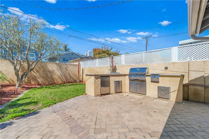 Entertainer's backyard featuring a built-in outdoor kitchen, BBQ, refrigerator, and plenty of room to relax and gather.
