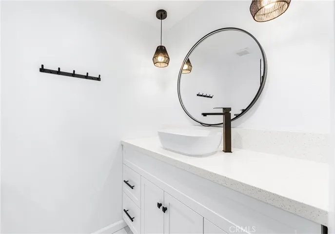 Designer vanity featuring a vessel sink, quartz countertops, matte black fixtures, and modern lighting.