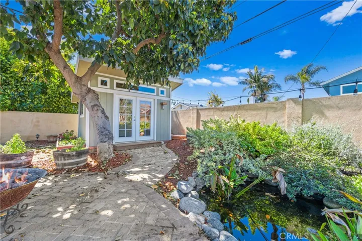 Charming backyard studio overlooking a peaceful pond beneath a mature avocado tree perfect as a home office, gym, creative space, or private retreat.