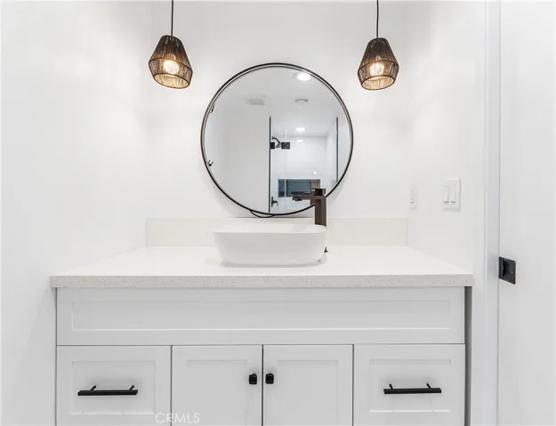 Designer vanity featuring a vessel sink, quartz countertops, matte black fixtures, and modern lighting.