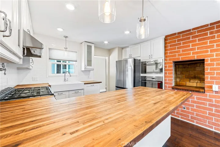 Beautifully remodeled kitchen showcasing designer finishes, built-in appliances, and an iconic indoor brick barbecue perfect for entertaining.