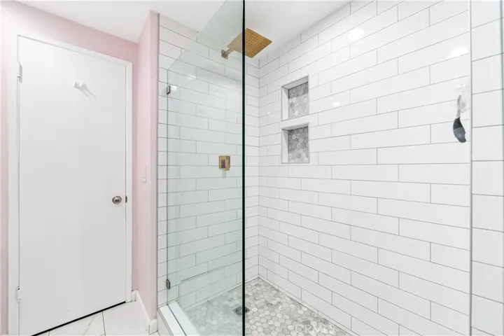 Luxurious walk-in shower featuring frameless glass, designer tile, dual niches, and a premium rain shower.