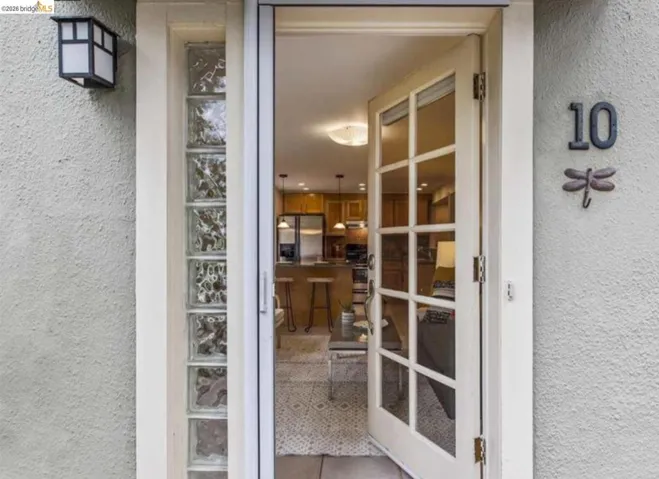 Entryway featuring a glass-paned door, textured exterior wall, and vertical glass block sidelight