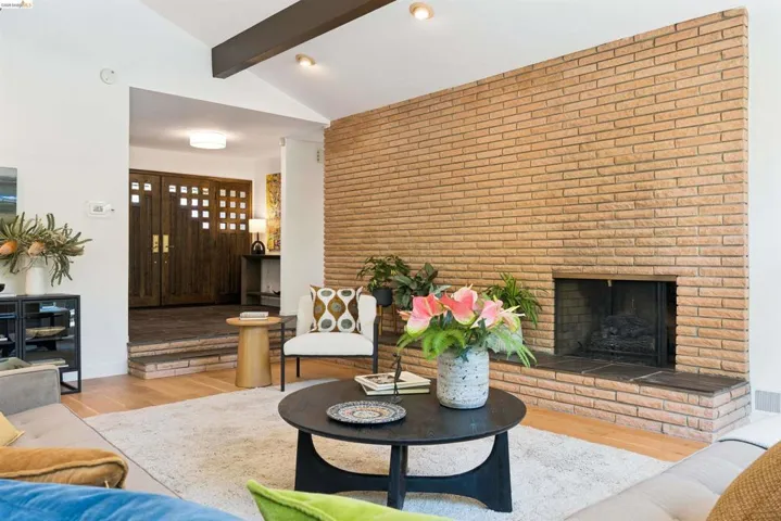 Expansive living area featuring a prominent brick fireplace with a raised hearth