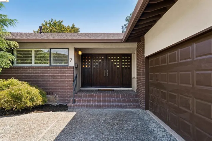 Brick facade with exposed aggregate concrete driveway and a brown panel garage door