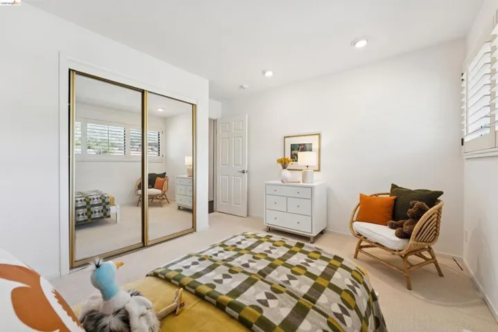 Light-filled room featuring plush carpet flooring, white walls, recessed lighting, and a window with plantation shutters