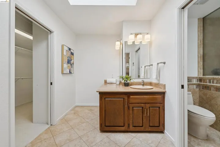 Bathroom vanity with wood-finish cabinetry, a circular sink, and a light-toned countertop