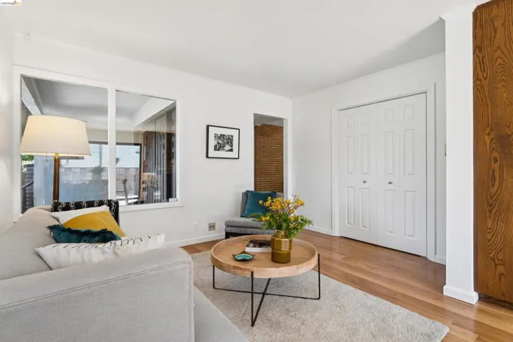 Living area featuring light wood-finish flooring, white walls, and a large window