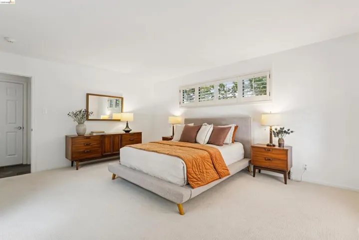Light-filled room featuring white walls, plush carpeting, and plantation shutter windows