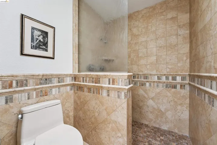 Bathroom featuring a glass-enclosed shower, tiled walls, and a tiled shower floor