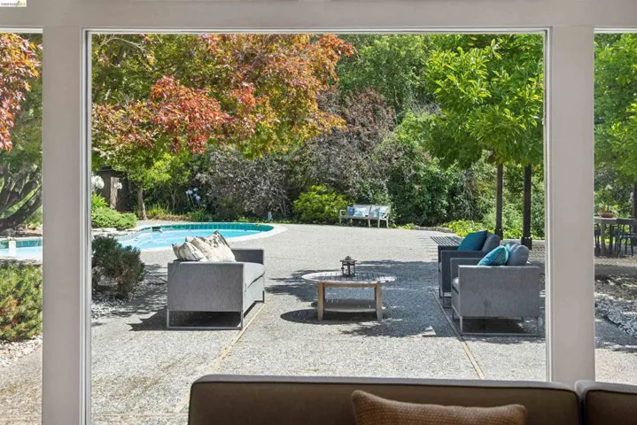 Expansive outdoor living area featuring a swimming pool, concrete patio, and mature trees
