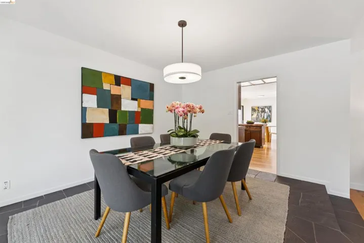 White walls and dark stone-look flooring enhance this dining space, featuring a modern ceiling light fixture