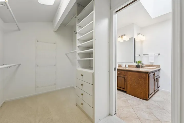 Walk-in closet featuring carpet flooring, integrated shelving, and multiple hanging rods