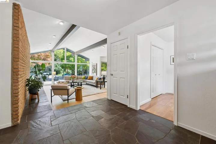 Foyer featuring natural stone tile flooring and a brick accent wall