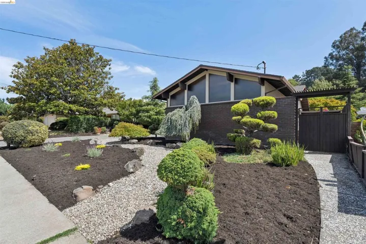 Mid-century modern exterior featuring a dark brick facade and a distinct low-pitched roofline