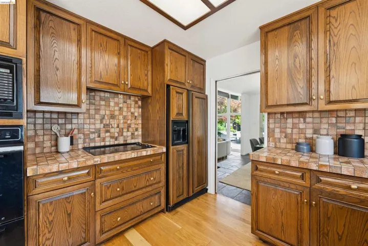 Kitchen featuring abundant wood cabinetry, tile countertops, and a tile backsplash