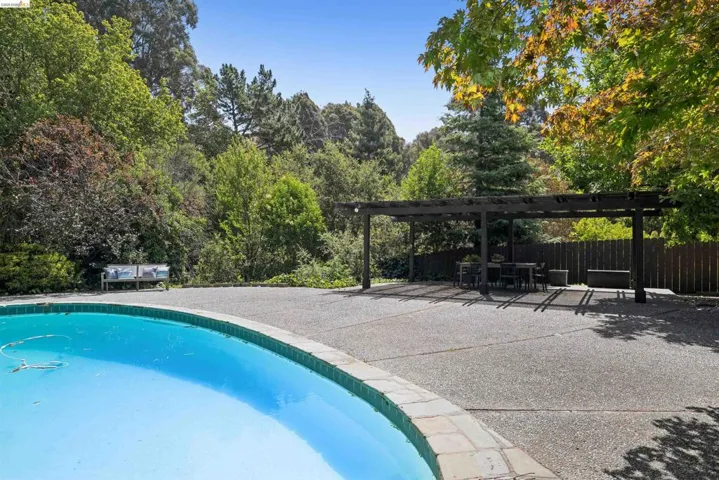 Expansive outdoor patio featuring an inground swimming pool with stone coping and a large exposed aggregate deck
