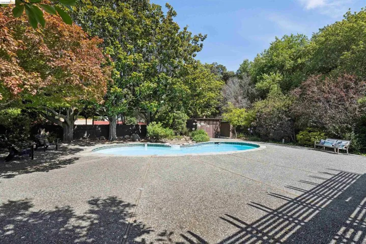 Freeform swimming pool surrounded by a large aggregate​​‌​​​​‌​​‌‌​​‌​​​‌‌​​​‌​​‌‌​​‌‌​​‌‌​​​​ patio