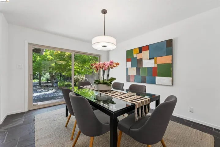 Sliding glass doors opening to outdoor grounds, slate-style flooring, white walls, and a contemporary ceiling light fixture
