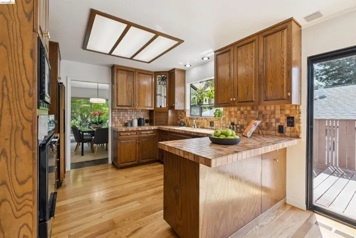 Kitchen featuring wood-finish cabinetry, tile countertops, and a complementary tile backsplash