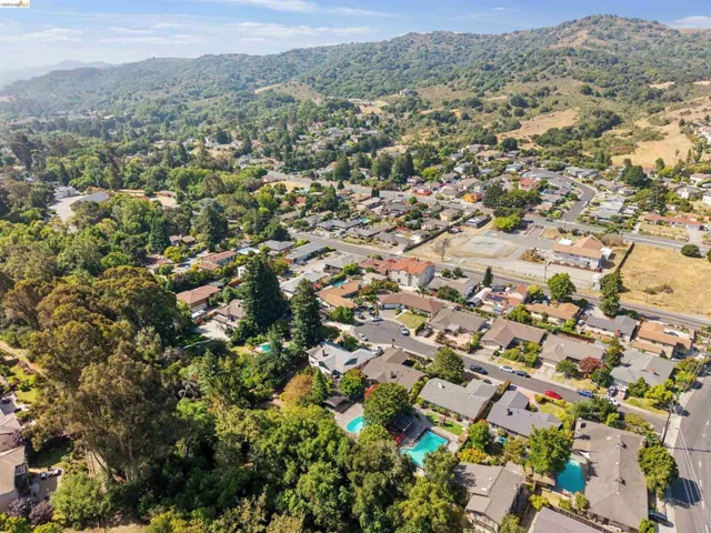Aerial perspective showcasing a residential community nestled against a lush, tree-covered hillside