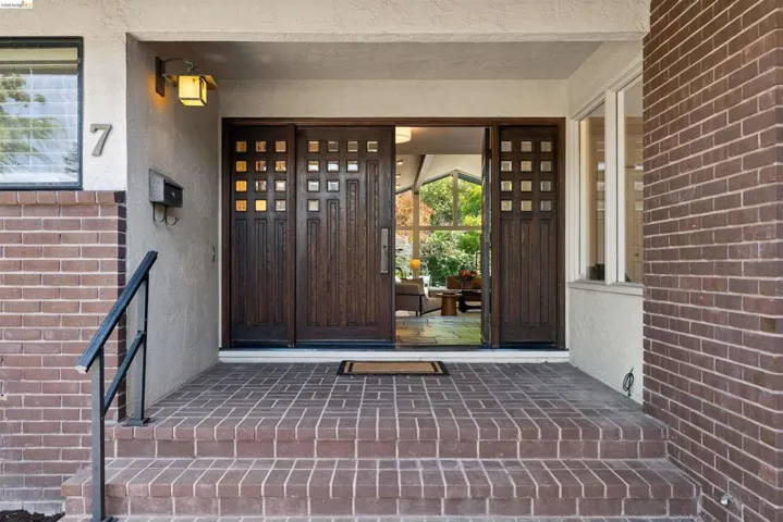 Entryway with a brick facade and steps leading to a recessed porch