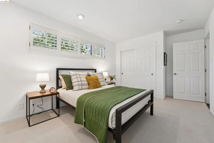 Bright bedroom featuring white walls and light-colored carpeting