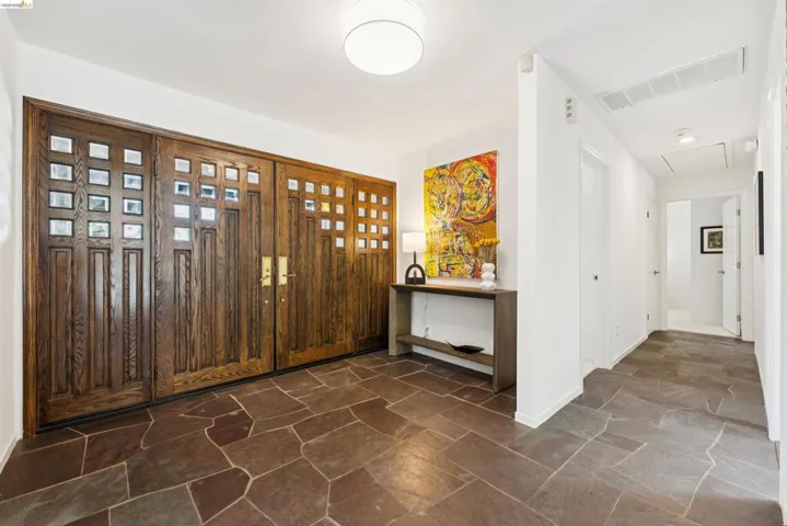 Entry foyer featuring dark wood double doors with multiple glass inserts and natural stone flooring