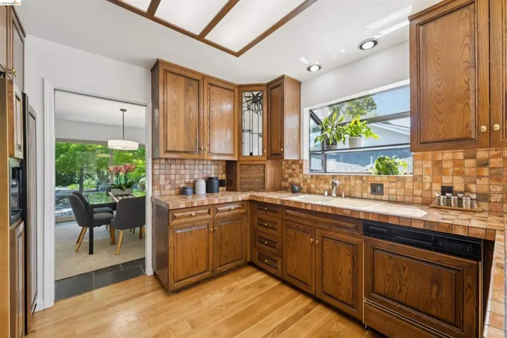 Kitchen featuring wood cabinetry, tile countertops, and a tile backsplash