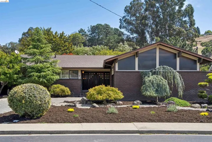 Mid-century modern exterior featuring a brown brick facade and an A-frame roofline with prominent triangular windows