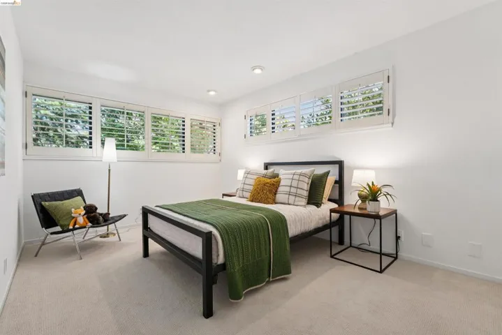 Well-lit room featuring multiple windows with plantation shutters, recessed lighting, and light-toned carpet flooring