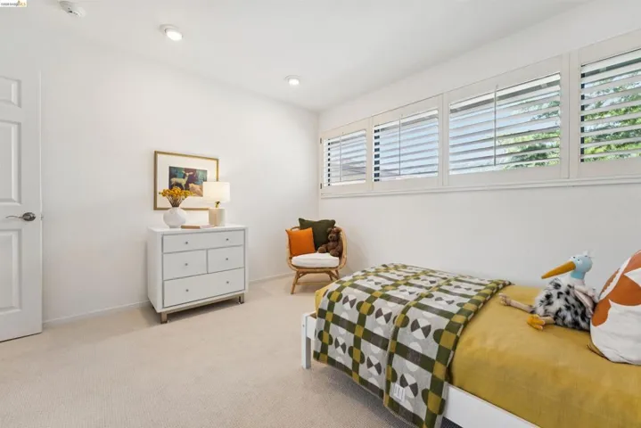 Light-filled room featuring white walls, recessed lighting, white plantation shutters, and neutral carpeting
