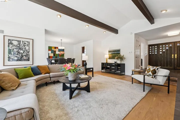 Expansive living area featuring vaulted ceilings with exposed beams, recessed lighting, and wood-finish flooring