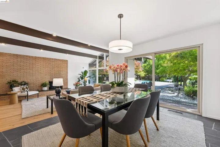 Dining area with slate tile flooring, a contemporary pendant light fixture, and a large sliding glass door