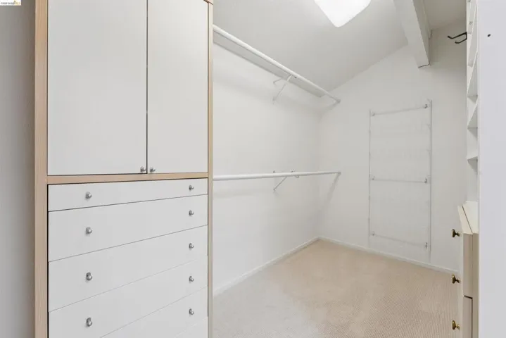 Walk-in closet with built-in cabinetry, white wire shelving, and neutral carpeting