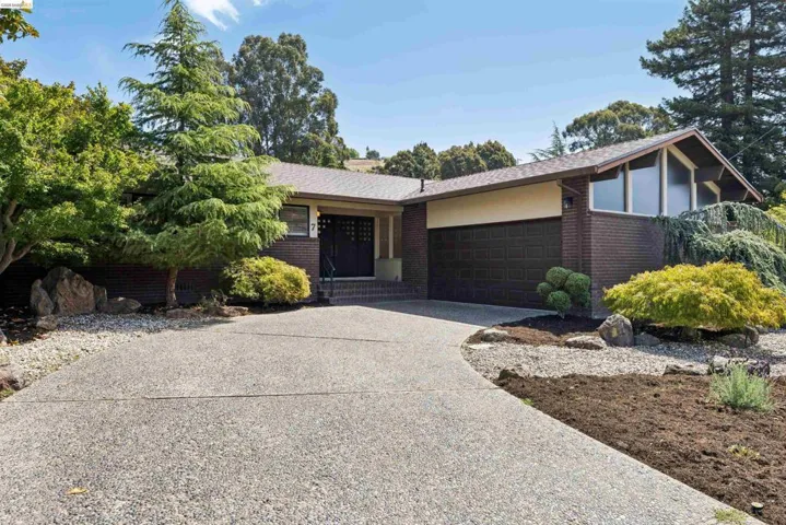 Mid-century modern residence featuring a dark brick facade, an exposed aggregate driveway, and a two-car garage