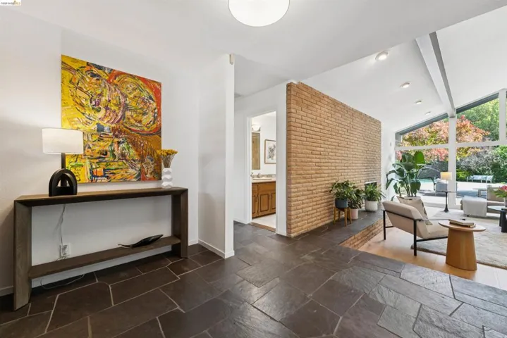 Slate tile flooring extending into a spacious living area with exposed brick accents, high vaulted ceilings, and extensive window walls