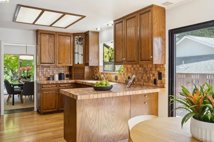 U-shaped kitchen featuring wood cabinetry, tile countertops, and a mosaic tile backsplash