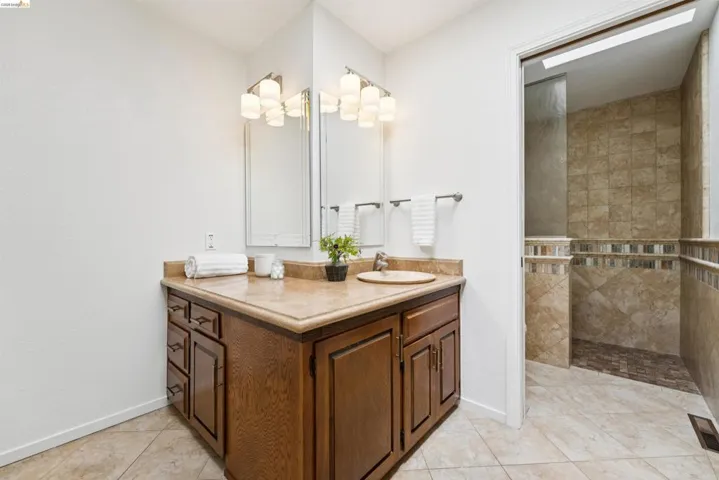 Bathroom vanity with wood cabinetry, an integrated sink, and a light-colored countertop