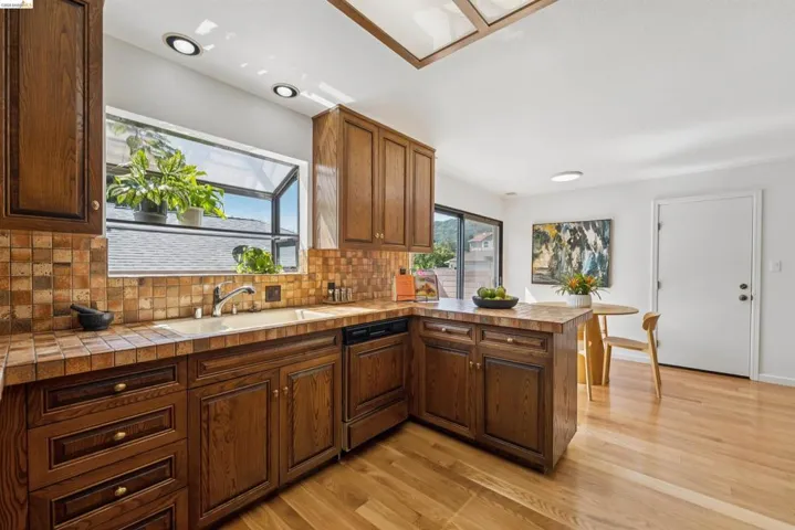Kitchen featuring rich wood cabinetry, tile countertops, and a tile backsplash