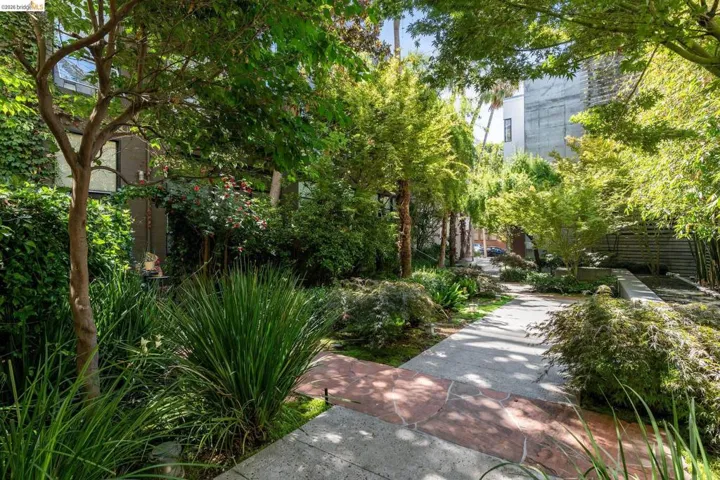 Landscaped pathway featuring mature trees and diverse plantings, creating a private outdoor environment